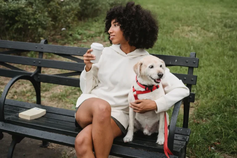 Woman sitting with a shaggy dog on a park bench